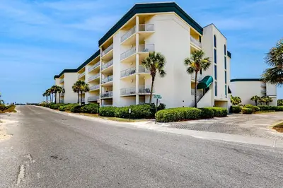 an empty street in front of a building with palm trees at Gulf-front 3-bedroom condo with balconies off each bedroom & pickleball in Santa Rosa Beach