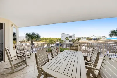 a wooden table and chairs on a deck with a view of the ocean at Charming suite with spacious balcony pools tennis & pickleball in Santa Rosa Beach