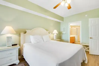 a bedroom with a white bed and a ceiling fan at Charming suite with spacious balcony pools tennis & pickleball in Santa Rosa Beach