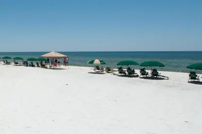 a group of chairs and umbrellas on a beach at Charming suite with spacious balcony pools tennis & pickleball in Santa Rosa Beach