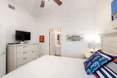 a white bedroom with a bed and a tv at Dog-friendly 4th-floor 3-bedroom condo with stunning Gulf views & pickleball in Santa Rosa Beach