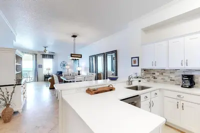 a kitchen with white cabinets and a dining room at Dog-friendly 4th-floor 3-bedroom condo with stunning Gulf views & pickleball in Santa Rosa Beach