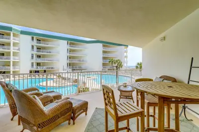 a patio with a table and chairs and a pool at Two-bedroom with bunks balcony overlooking pool & on-site pickleball in Santa Rosa Beach