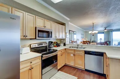 a kitchen with wooden cabinets and a stove top oven at Gorgeous 3-bedroom condo with stunning view spacious balcony & pickleball in Santa Rosa Beach