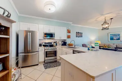 a kitchen with white cabinets and a stainless steel refrigerator at Charming two-bedroom with bunks balcony overlooking pool & pickleball in Santa Rosa Beach