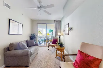a living room with a couch and a chair at Charming two-bedroom with bunks balcony overlooking pool & pickleball in Santa Rosa Beach