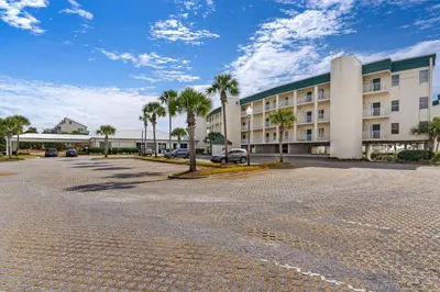 a parking lot in front of a building with palm trees at Charming two-bedroom with bunks balcony overlooking pool & pickleball in Santa Rosa Beach