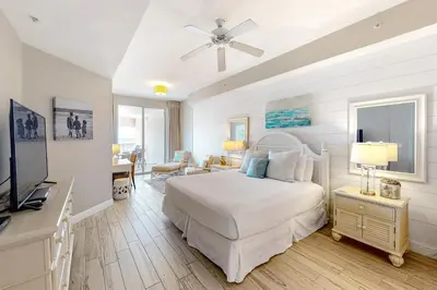 a white bedroom with a bed and a television at Amazing views at this renovated 4rth-floor condo with lagoon pool & pickleball in Santa Rosa Beach