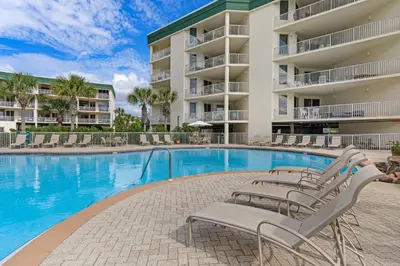 a swimming pool with lounge chairs in front of a building at Amazing views at this renovated 4rth-floor condo with lagoon pool & pickleball in Santa Rosa Beach