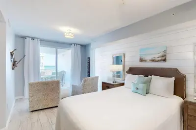 a bedroom with a white bed and a chair at Gorgeous condo with pool & Gulf view stunning decor bunk beds & pickleball in Santa Rosa Beach