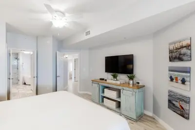 a bedroom with a bed and a flat screen tv at Gorgeous condo with pool & Gulf view stunning decor bunk beds & pickleball in Santa Rosa Beach