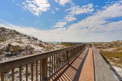 a boardwalk leading to the beach on a sunny day at Gorgeous condo with pool & Gulf view stunning decor bunk beds & pickleball in Santa Rosa Beach