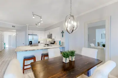a kitchen and dining room with a wooden table and chairs at Gorgeous condo with pool & Gulf view stunning decor bunk beds & pickleball in Santa Rosa Beach
