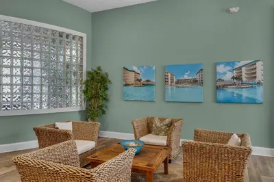 a living room with chairs and a table and paintings on the wall at Super-comfy Seagrove condo with spacious pool-view balcony & pickleball in Santa Rosa Beach