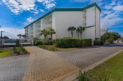 a white building with palm trees in front of it at Super-comfy Seagrove condo with spacious pool-view balcony & pickleball in Santa Rosa Beach