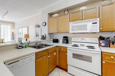 a kitchen with white appliances and wooden cabinets at Super-comfy Seagrove condo with spacious pool-view balcony & pickleball in Santa Rosa Beach