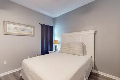 a bedroom with a white bed and a window at Attractive home with spacious balcony pool view & pickleball - near beach in Santa Rosa Beach