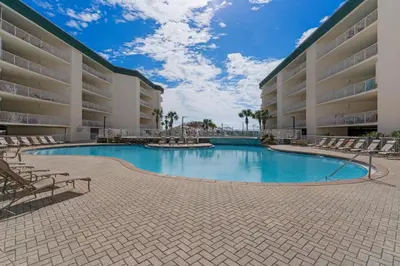 a swimming pool in front of a large building at Attractive home with spacious balcony pool view & pickleball - near beach in Santa Rosa Beach