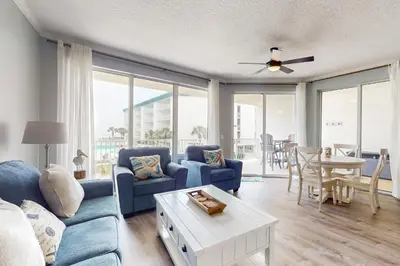 a living room with a blue couch and a table at Attractive home with spacious balcony pool view & pickleball - near beach in Santa Rosa Beach