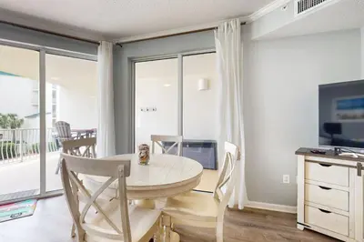 a dining room with a table and a television at Attractive home with spacious balcony pool view & pickleball - near beach in Santa Rosa Beach