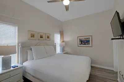 a white bedroom with a white bed and a television at Bright Gulf-view condo with balcony pool seasonal beach service & pickleball in Santa Rosa Beach