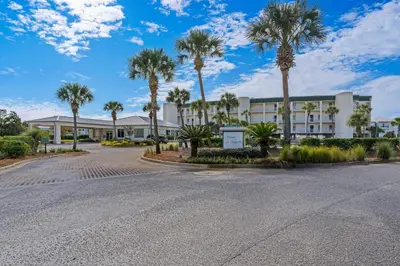 an empty street in front of a building with palm trees at Bright Gulf-view condo with balcony pool seasonal beach service & pickleball in Santa Rosa Beach
