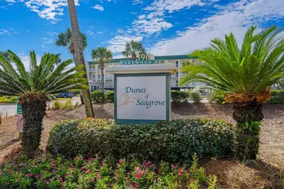 a sign in front of a hotel with palm trees at Bright Gulf-view condo with balcony pool seasonal beach service & pickleball in Santa Rosa Beach