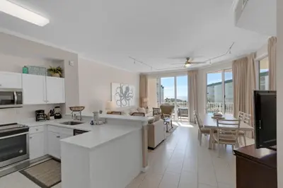a kitchen with white appliances and a living room at Bright Gulf-view condo with balcony pool seasonal beach service & pickleball in Santa Rosa Beach