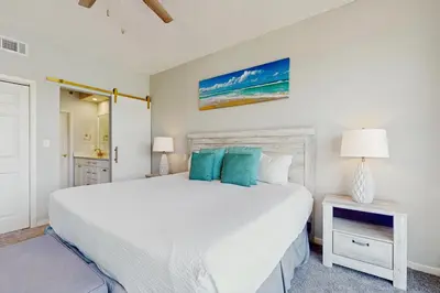 a bedroom with a large white bed with blue pillows at Airy beachfront condo with balcony views lagoon pool tennis & pickleball in Seacrest