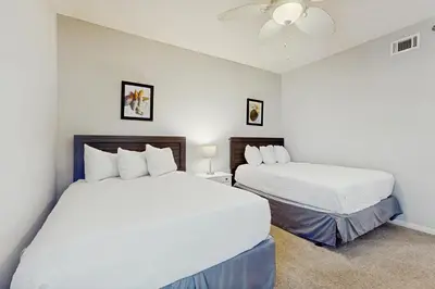 a bedroom with two beds and a ceiling fan at Airy beachfront condo with balcony views lagoon pool tennis & pickleball in Seacrest