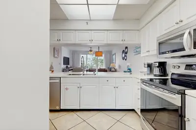 a white kitchen with white cabinets and a sink at Beautiful 3rd-floor villa with hot tub tennis pickleball & balcony with views in Seacrest