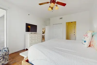 a white bedroom with a bed and a ceiling fan at Beautiful 3rd-floor villa with hot tub tennis pickleball & balcony with views in Seacrest