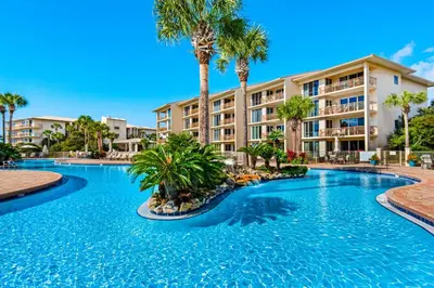 a swimming pool with palm trees in front of a building at Beautiful 3rd-floor villa with hot tub tennis pickleball & balcony with views in Seacrest