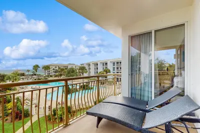 a balcony with a blue chair and a view of the beach at Lovely condo with pool hot tub modern furnishings pickleball - near beach in Seacrest