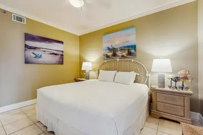 a bedroom with a white bed and two paintings on the wall at Lovely condo with pool hot tub modern furnishings pickleball - near beach in Seacrest
