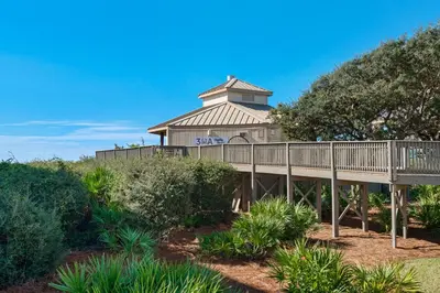 a boardwalk leading to a building with a tower at Spacious getaway with Gulf view beach access tennis & pickleball in Seacrest