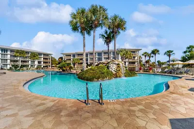 a swimming pool at a resort with palm trees at Conveniently located Gulf condo with spacious layout pool & pickleball in Seacrest