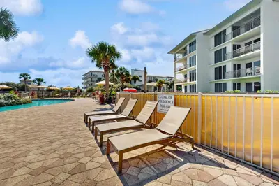 a row of lounge chairs sitting next to a pool at Conveniently located Gulf condo with spacious layout pool & pickleball in Seacrest