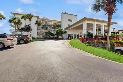 a street in front of a building with palm trees at Conveniently located Gulf condo with spacious layout pool & pickleball in Seacrest