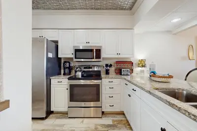 a kitchen with white cabinets and stainless steel appliances at Condo with pickleball - steps from the Gulf & quick walk to dining & shops in Seacrest