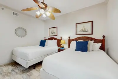 two white beds in a room with a ceiling fan at Condo with pickleball - steps from the Gulf & quick walk to dining & shops in Seacrest
