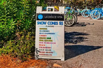 a sign for snow cones in front of a group of bikes at Condo with pickleball - steps from the Gulf & quick walk to dining & shops in Seacrest