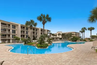 a pool at the resort with palm trees and condos at Gulf-front condo with bicycles lazy river & pickleball in Seacrest