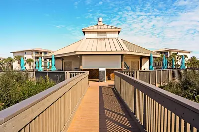 a boardwalk leading to a house with a building at Gulf-front condo with bicycles lazy river & pickleball in Seacrest