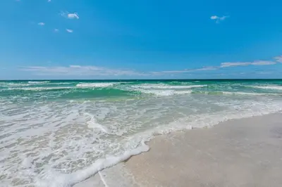 a beach with the ocean on a sunny day at Gulf-front condo with bicycles lazy river & pickleball in Seacrest