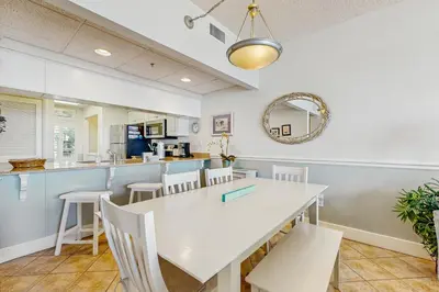 a dining room with a white table and chairs at Gulf-front condo with bicycles lazy river & pickleball in Seacrest