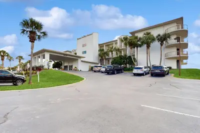 a parking lot in front of a building with palm trees at Elegant getaway with stunning view lagoon pool & pickleball - close to shops in Seacrest