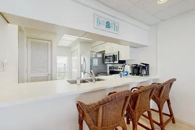 a kitchen with two chairs and a counter with a sink at Gorgeous beach condo with furnished balcony panoramic view & pickleball in Seacrest