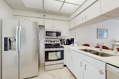 a kitchen with stainless steel appliances and white cabinets at Gorgeous beach condo with furnished balcony panoramic view & pickleball in Seacrest
