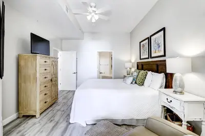 a white bedroom with a bed and a tv at Beautiful 2nd-floor condo in Seagrove Beach with beach ambience & pickleball in Santa Rosa Beach
